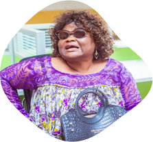 A member of CAMAB Women in dark glasses, a white cane resting beside her.