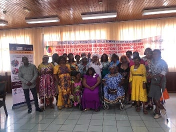 Group photograph under a banner reading 'Ministere de la Promotion de la Femme et de la Famille - Atelier de mediation et de renforcement des capacites des membres de la plateforme et associations des handicapes en vue d'une meilleure...