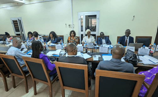 Boardroom meeting with name cards, delegates seated around a rectangular table.