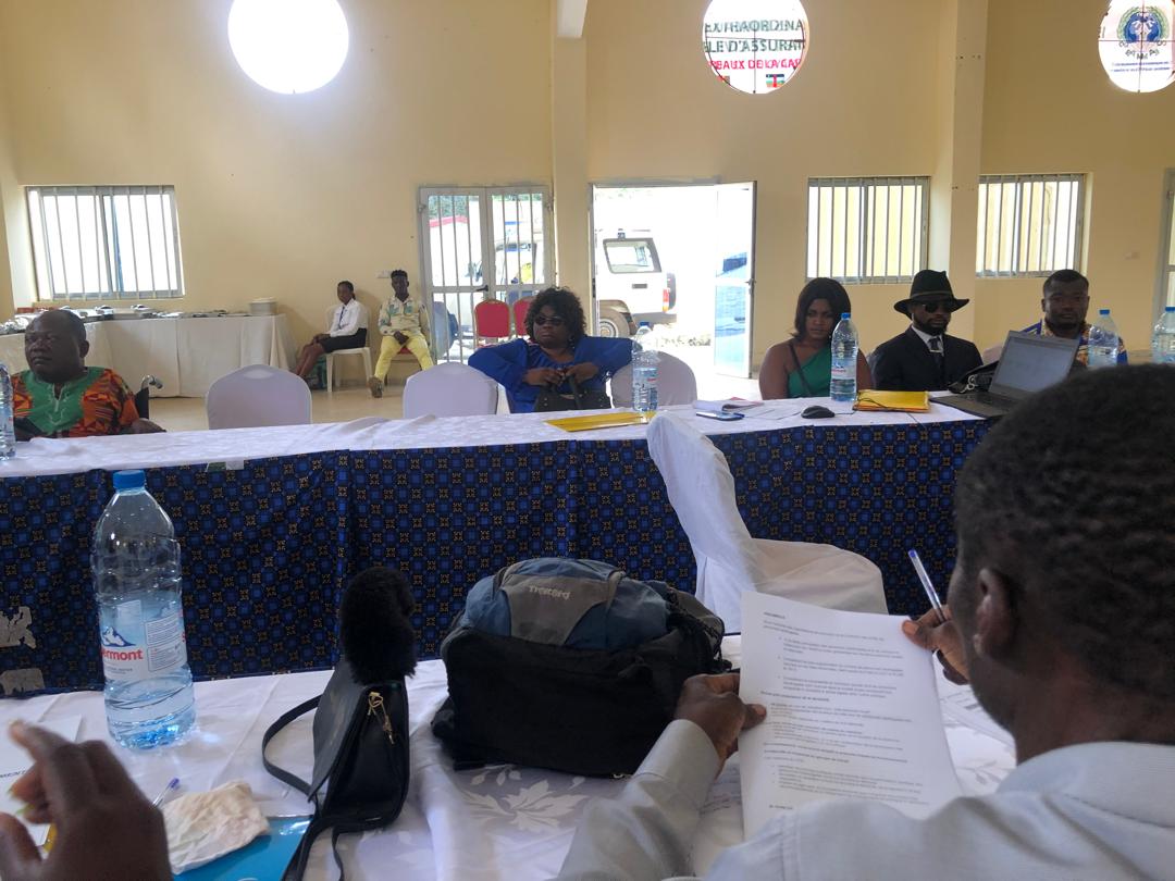 Training room with blue-draped tables; a participant in the foreground reads a document.