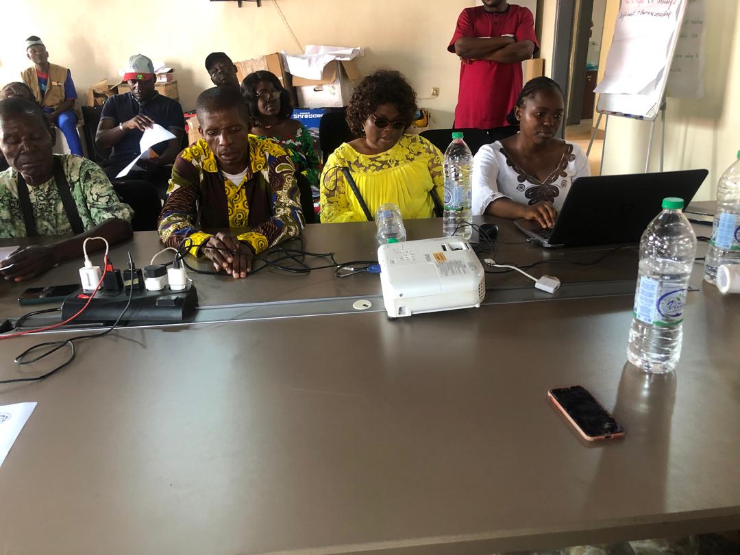 Participants at a table with a projector and laptop; cabling and equipment in the foreground.